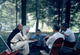 Daniel Berrigan is pictured in a blue plaid shirt in center with Merton seated on the photo's left and Phillip Berrigan on the far right (other person identified as Tony Walsh). Photo from August 1962 retreat.